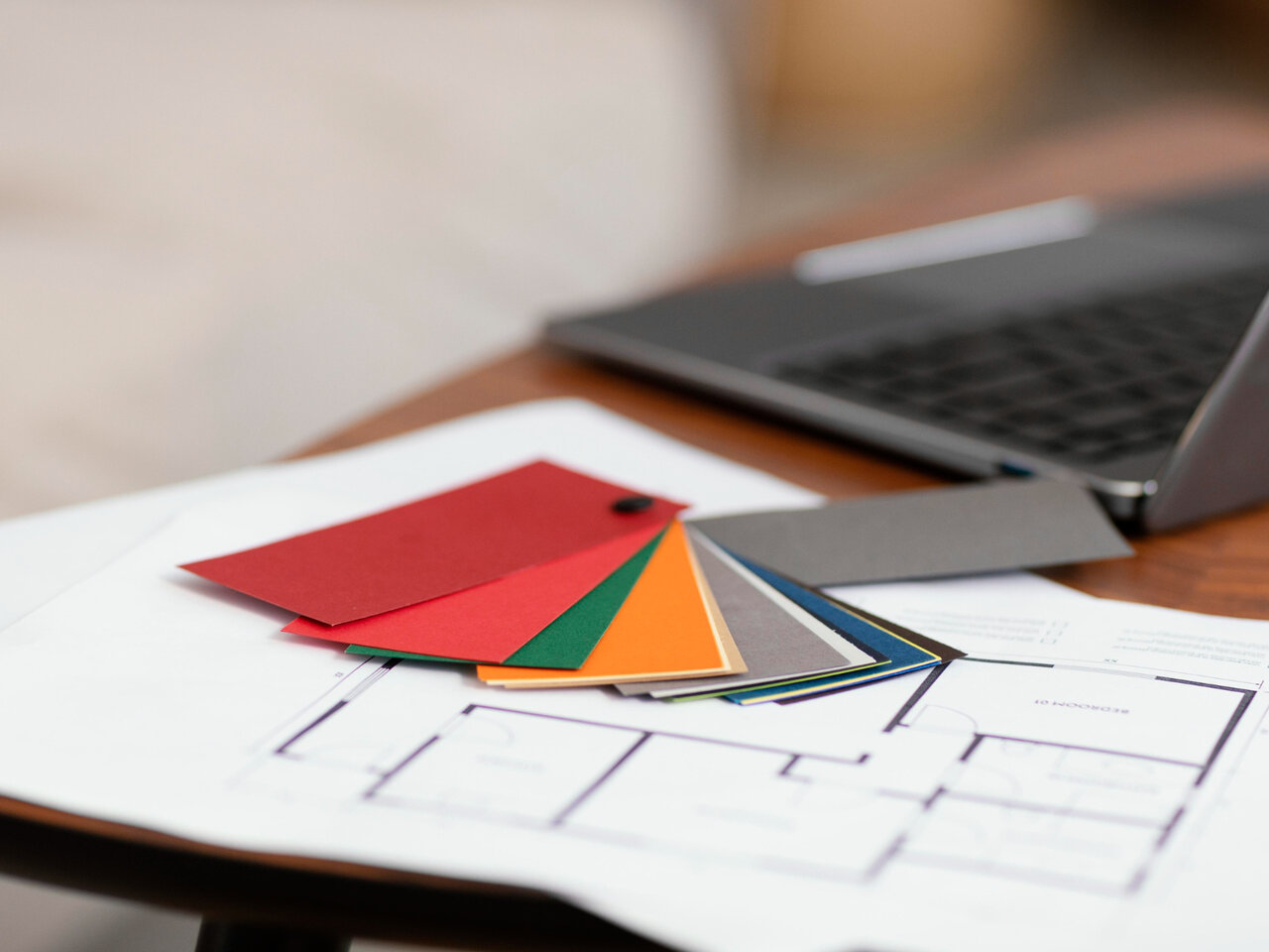 Design de interiores: Paleta de cores em cima de uma mesa ao lado de um notebook e um projeto.