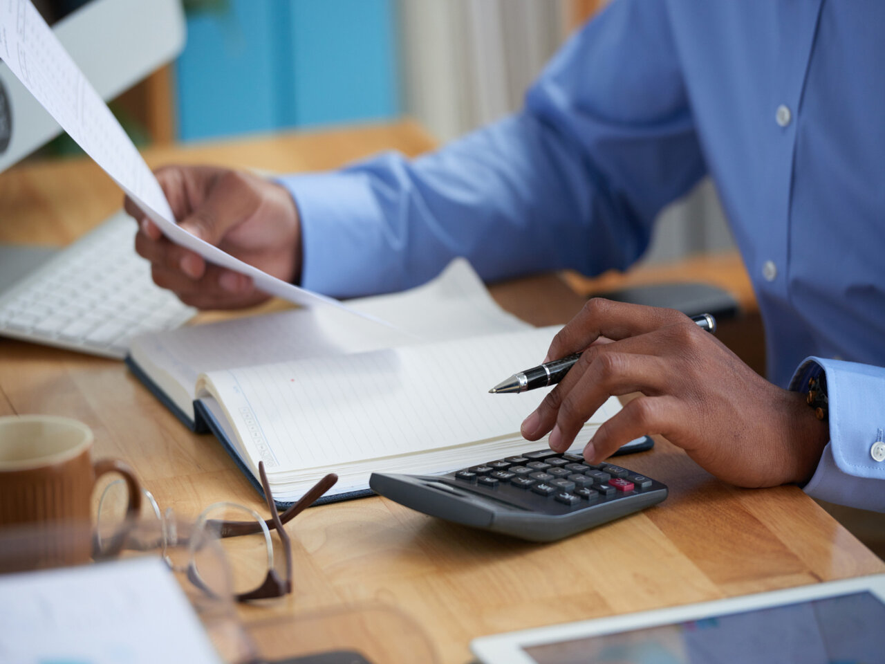 Especialista em remuneração estratégica em seu escritório utilizando uma calculadora enquanto lê um documento.