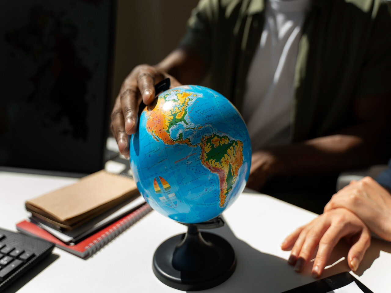 Dois alunos em uma mesa, segurando um globo terrestre, durante uma aula na faculdade de Geografia.