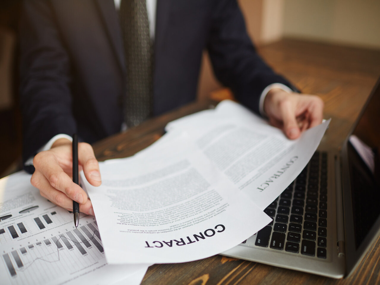 Pós em Direito Empresarial: advogado empresarial sentado em sua mesa enquanto analisa um contrato para seu cliente.
