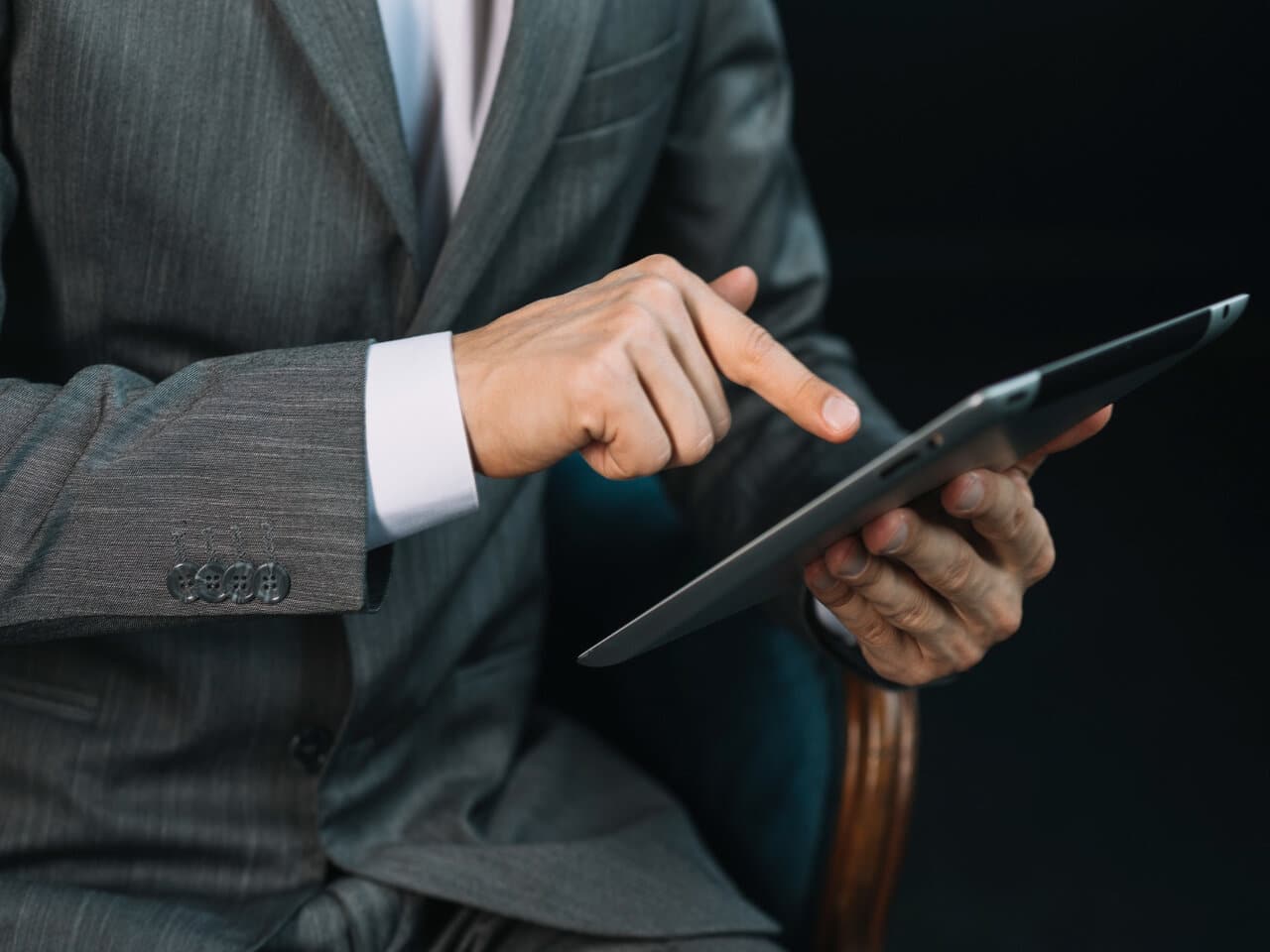 Advogado de direito digital em seu escritório, sentado em uma cadeira enquanto utiliza um tablet para trabalhar