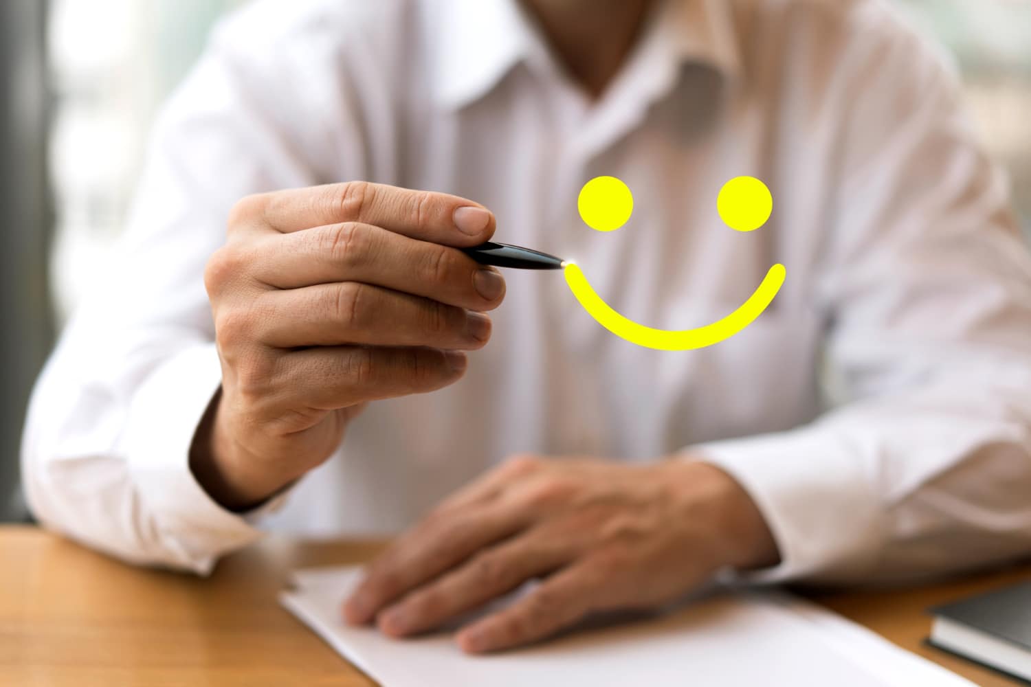Crítica construtiva: imagem de um empresário segurando uma caneta como se estivesse desenhando um rosto feliz em amarelo na tela