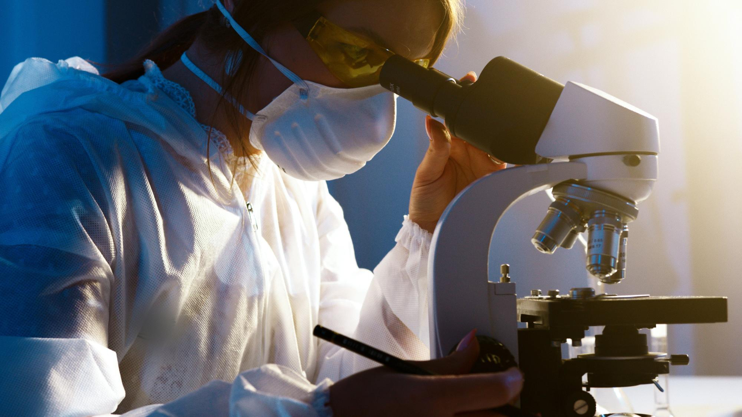 Biomédica registrada no Conselho Regional de Biomedicina, em um laboratório, utilizando um microscópio para analisar amostras