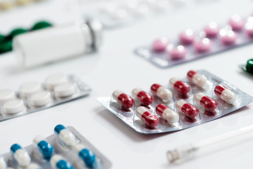 Mesa com algumas cartelas de remédio de diversas cores, representando o que é farmacologia