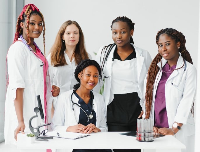 Grupo de médicas reunidas em um consultório posando sorridentes para a foto e representando as mulheres na medicina