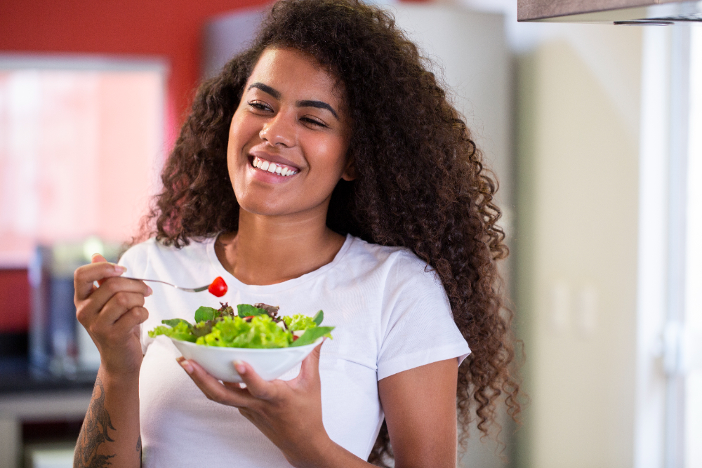 Jovem estudante segurando um prato de salada enquanto mantém uma alimentação saudável