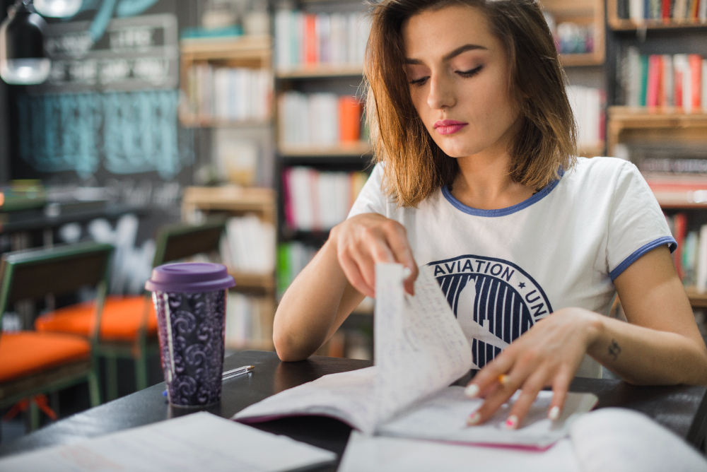 Jovem estudante em uma biblioteca, estudando concordância nominal enquanto se preparar para o ENEM
