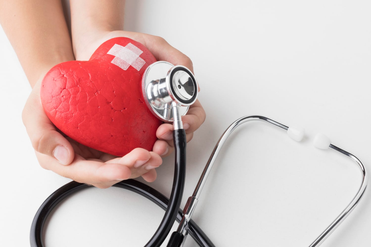 Medico cardiologista segurando uma réplica de um coração junto a um estetoscópio