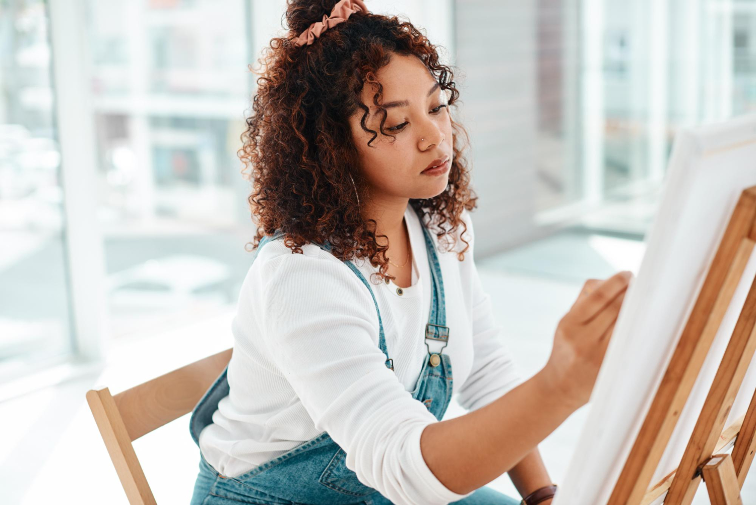 Jovem estudante pintando em uma tela, um hobby adquirido em seu tempo livre.