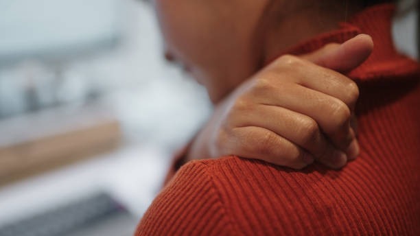 Homem com uma das mãos apertando a região da clavícula, por consequências de dores causadas pela fibromialgia