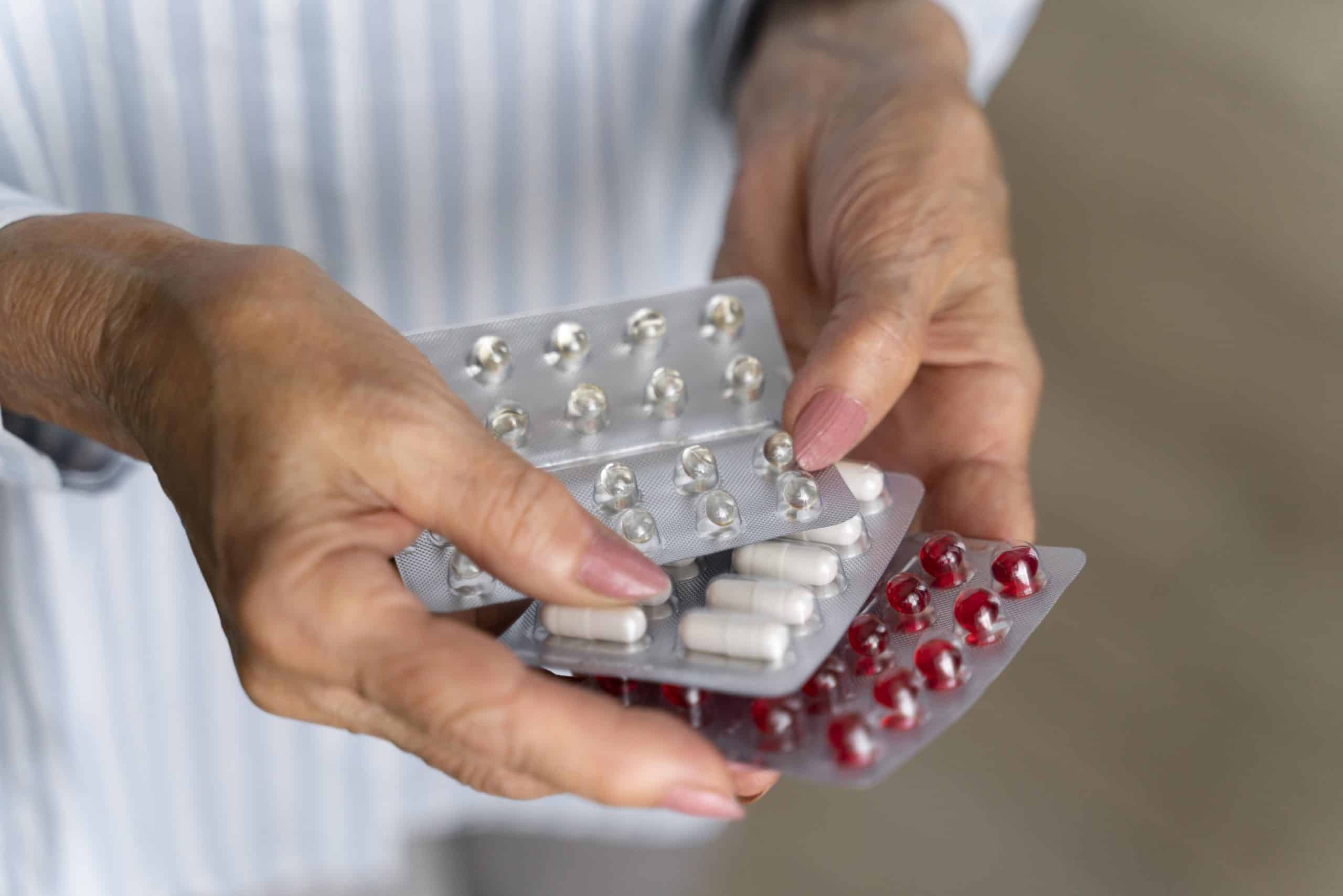 Pessoa segurando cartelas de medicamentos durante alerta sobre os riscos da automedicação