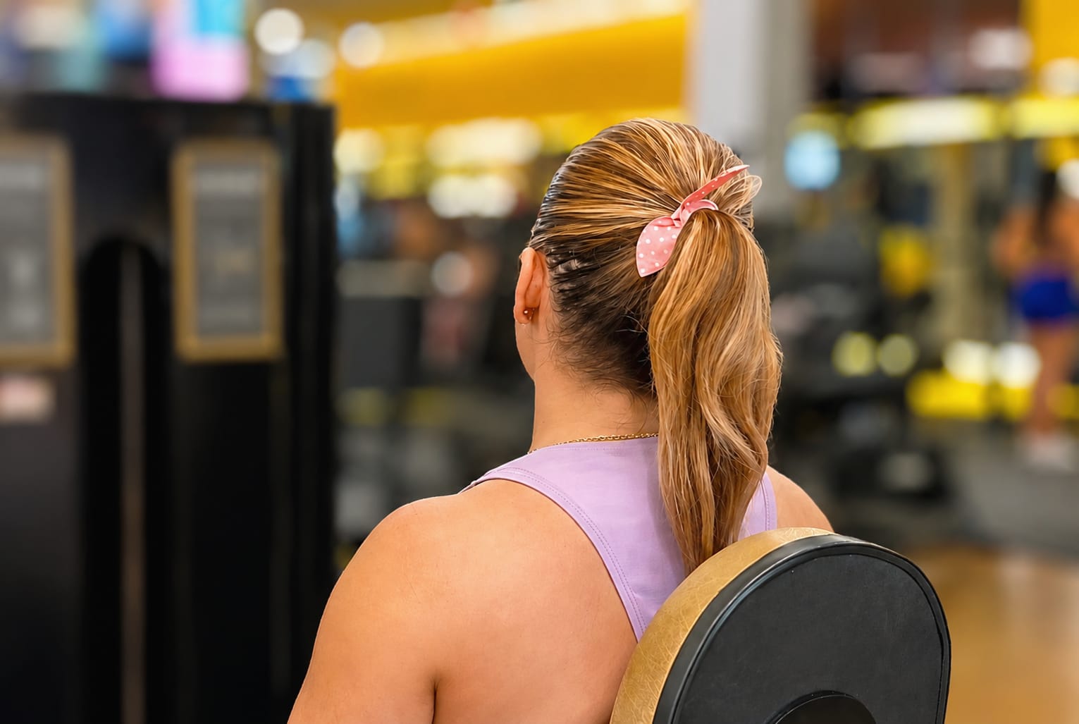 Mulher praticando exercício físico em academia, ilustrando os cuidados com a saúde capilar após exercícios físicos.